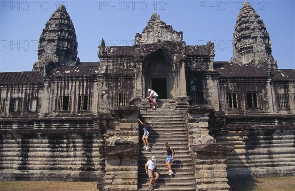 CAMBODIA, Siem Reap Province, Angkor Wat, Western tourists climbing steep and narrow set of steps of enclosure wall at the rear of the temple complex.