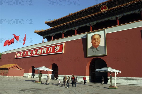 CHINA, Beijing, Tiananmen Square, Tiananmen Monument aka Gate of Heavenly Peace with portrait of Mao on the front and two guards standing under square umbrellas