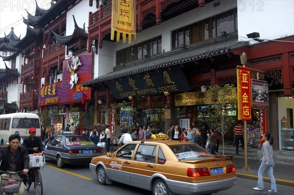 CHINA, Shanghai, Urban shopping street with passing traffic and pedestrians and traditional architecture