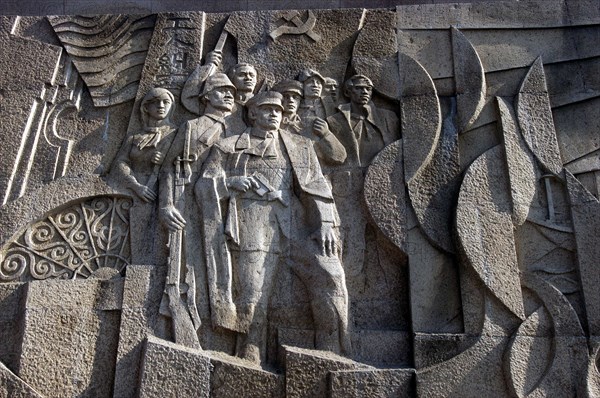CHINA, Shanghai, Carved stone political mural depicting figures with guns with communist symbol above