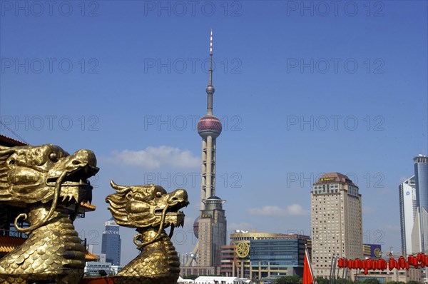 CHINA, Shanghai, City skyline and Television Tower with golden dragon head statues in the foreground