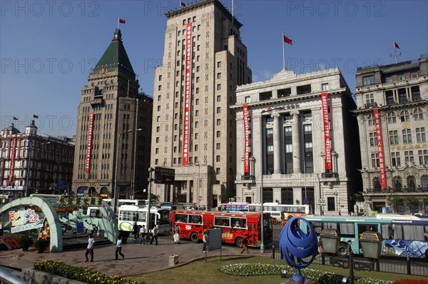 CHINA, Shanghai, The Bund aka Zhong Shan Road. View along the 1930s style waterfront architecture including the Peace Hotel and the Bank of China from park with modern sculpture in the foreground