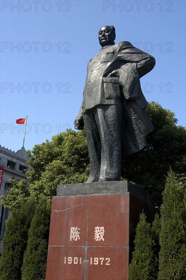 CHINA, Shanghai, The Bund. Statue of Mao against a backdrop of formal bushes and a flag fly from the roof of the building in the background