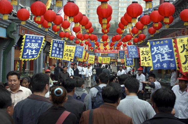 CHINA, Beijing, Busy street scene with red lanterns hanging in rows overhead