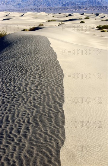 USA, California, Death Valley, View along the ridge of a sand dune in the desert landscape with a rocky hills in the distance