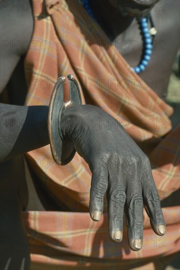UGANDA, Karamoja, Tribal Poeple, Cropped shot of Karamojong Dodoth warrior displaying wrist knife used for cutting meat and as a weapon before the use of guns
