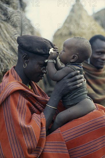UGANDA, Karamoja, Portrait of Karamojong warrior holding his baby.