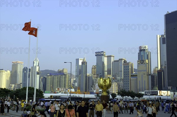 HONG KONG, General, Busy street scene with city skyline and crowds of people in the foreground