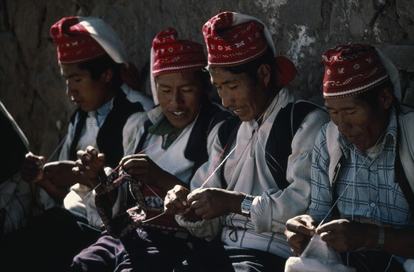 PERU, Puno, Lake Titicaca, Taquile Island.  Line of men knitting.