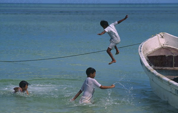 MEXICO, Yucatan, Celestun, Gulf of Mexico. Children jumping from fishing boat into the sea.