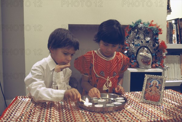 ENGLAND, Religion, Hinduism, Diwali Hindu Festival of lights with children lighting candles beside a picture of Lakshmi