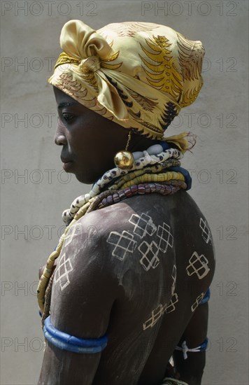 GHANA, Initiation Ceremony, Portrait of a Dipo girl dressed in venetian beads and gold earrings for her puberty initiation with painted crosses on her back and a headscarf