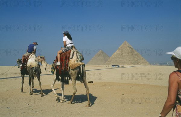 EGYPT, Cairo, Tourists on camels visiting the pyramids