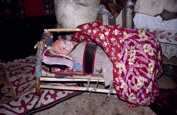 CHINA, Xinjiang Province, Altai Region, Kazakh baby in crib inside kigizuy or yurt.