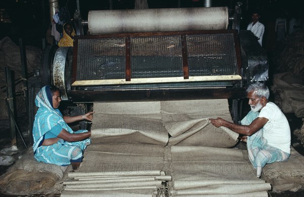 INDIA, West Bengal, Calcutta, Male and female workers in Fort Gloster jute mill drawing out lengths of jute from machinery.