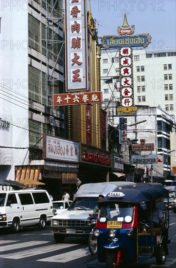 THAILAND, Bangkok, Street scene with tuk tuk and other traffic high rise buildings and advertising hoardings.