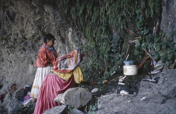 MEXICO, San Luis Potosi State, Sierra de Catorce, Huichol Indian women placing offerings at sacred shrine.