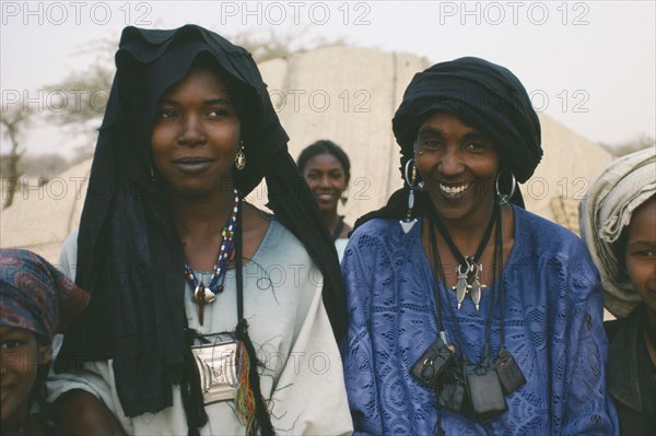 NIGER, Tribal People, Head and shoulders portrait of two Tuareg women near Tanout wearing typical jewellery and indigo coloured head dresses.