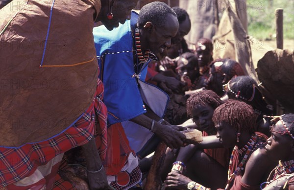 KENYA, Kajiado, Maasai Moran have the fat from a sacrificial cow daubed on them as well as taking a bite from its flesh during the ceremony that will bring them into manhood.
