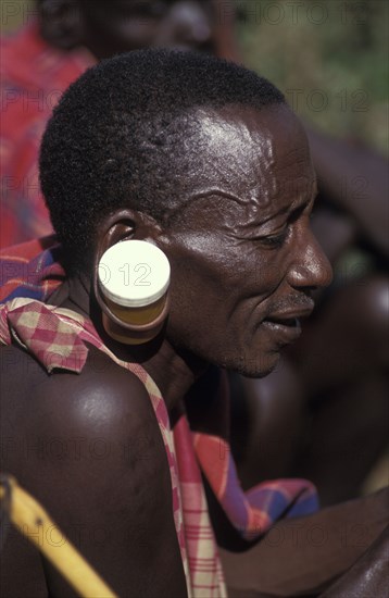 KENYA, , A maasai man at an intiation ceremony for the Moran coming into manhood with ears stretched with a pill container.