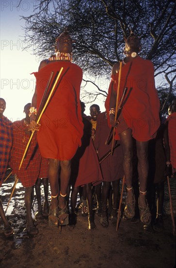 KENYA, Kajiado, Maasai moran measure each others capacity to jump springing from a standing start. They often sing in a group as they do this each taking turns to jump.