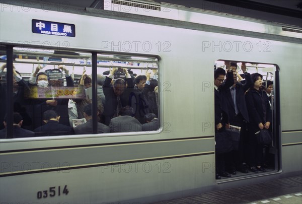 JAPAN, Honshu, Tokyo, Subway train at a platform with passengers crowded on