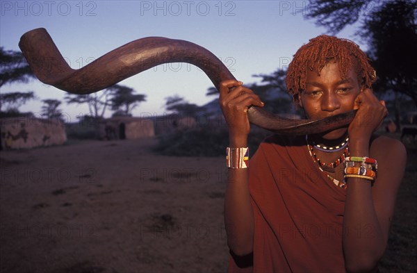 KENYA, Kajiado, A Maasai Moran blows an Ikudu horn as part of innitiation ceremony bringing the young Maasai Moran into their manhood. On blowing this horn many of the Moran go into trance.