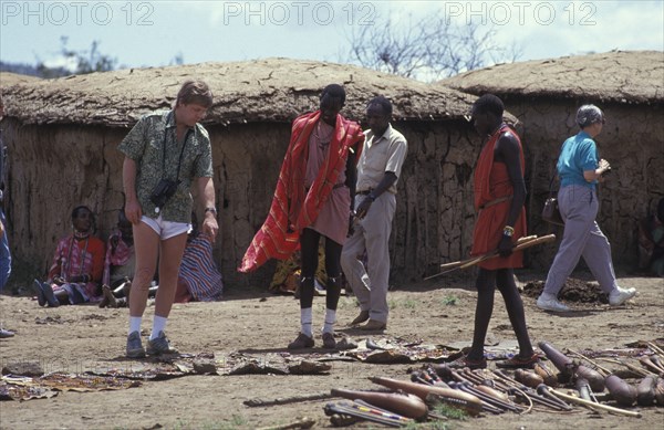 KENYA, , An American tourist haggles with a Maasai man in a cultural manyatta set up to interface the Maasai directly with tourists.