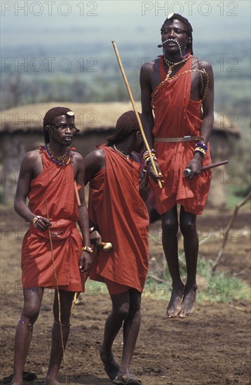 KENYA, Kajiado, Maasai Moran measure each others capacity to jump springing from a standing start. They often sing in a group as they do this each taking turns to jump.