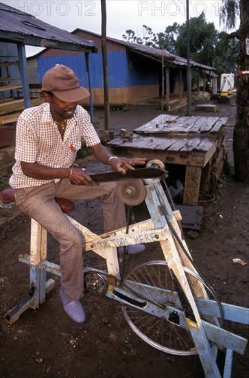KENYA, Loitokitok, Man sharpening a knife on a pedal powered knife grinder