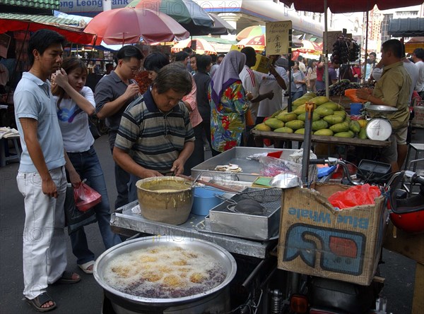 MALAYSIA, Kuala Lumpur, Chinatown, Market stalls selling various foodstuffs with customers waiting for hot food in the foreground