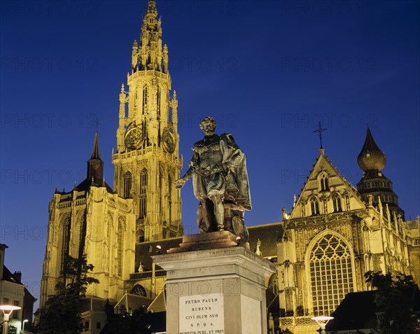 BELGIUM, Flemish Region, Antwerp, Cathedral of Notre Dame with statue of the seventeenth century artist Peter Paul Rubens in the foreground illuminated at night.