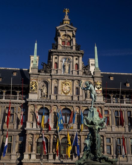 BELGIUM, Flemish Region, Antwerp, Grote Markt or Main Square.  The Brabo Fountain with the Town Hall facade hung with flags behind .