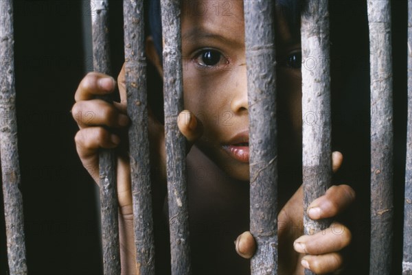 COLOMBIA, Amazonas, Santa Isabel, Portrait of a young Macuna Indian boy at the gate of his maloca.