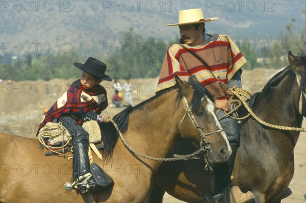 CHILE, Santiago, La  Barnechea, Man and young boy on horseback at the Fiesta de Cuasimodo held a week after Easter.