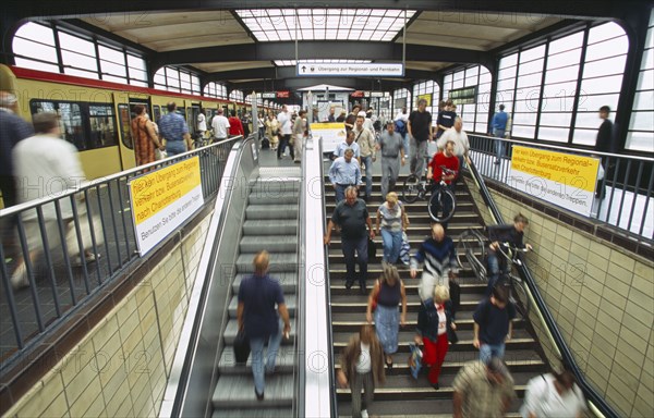 GERMANY, Berlin, Interior of the Zoologischer Garten Railway station with people on stairs to platform and waiting train.