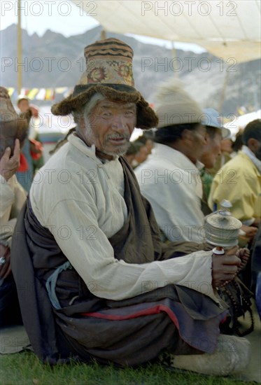 INDIA, Ladakh, Pilgrim with prayer wheel at the 14th Dalai Lamas birthday celebrations