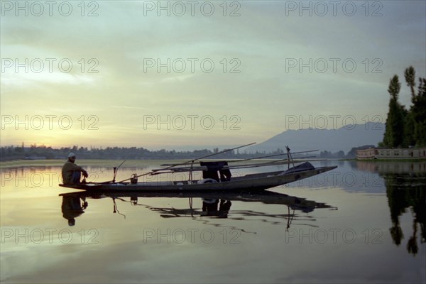 INDIA, Kashmir, Srinagar, Nagin Lake. Fisherman sitting at the very end of his canoe in the evening light