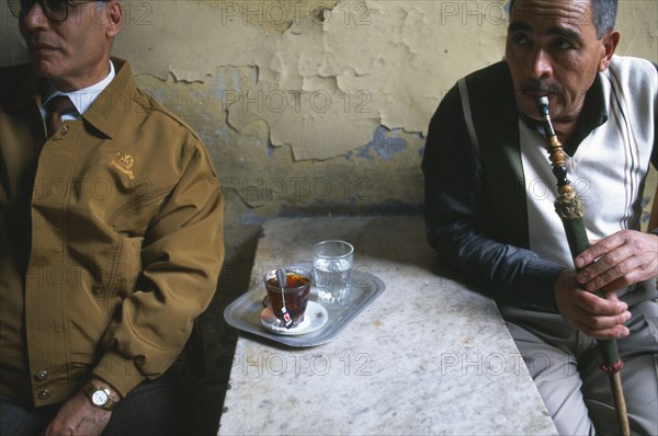 EGYPT, Nile Delta, Alexandria, Two men in street cafe one drinking tea and one smoking a sheesha waterpipe.