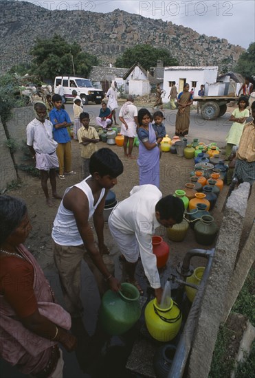 INDIA, Andhra Pradesh, Anantapur, People queuing with their plastic water pots to collect water from the common village tap.