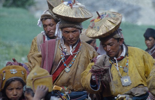 INDIA, Zanskar, Men in gold head dresses who stage a mock abduction to take bridegroom to meet bride in traditional Buddhist wedding ceremony.