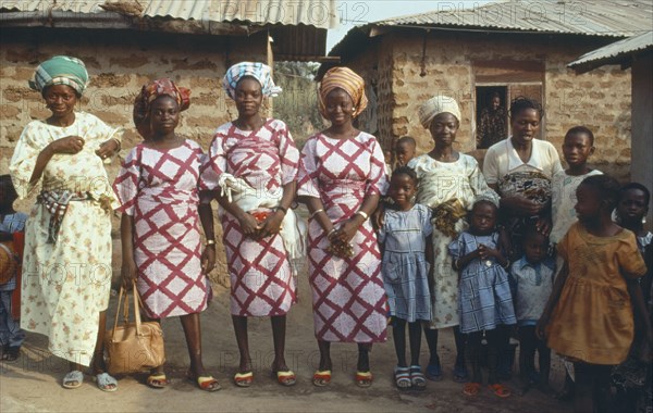 NIGERIA, Marriage, "Polygamy.  Wives of the same man, framed in window behind, wearing dresses made of the same material."