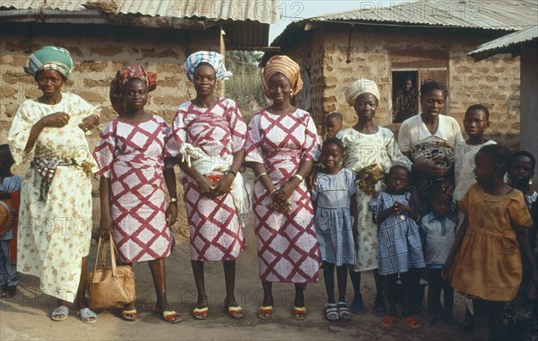 NIGERIA, Marriage, "Polygamy. Wives of the same man, framed in window behind, wearing dresses made of the same material."