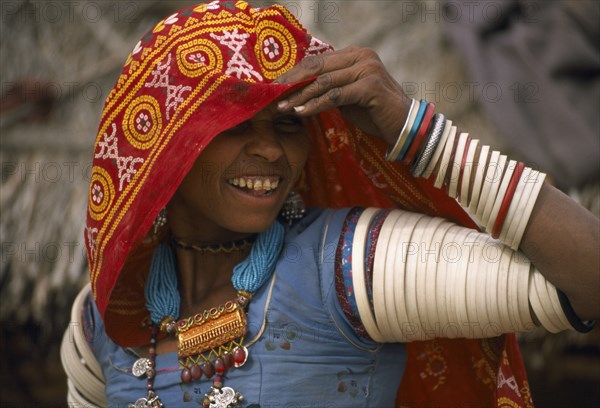INDIA, Rajasthan, Thar Desert, Bhansda village.  Smiling young woman from farming caste chodri wearing traditional jewellery.