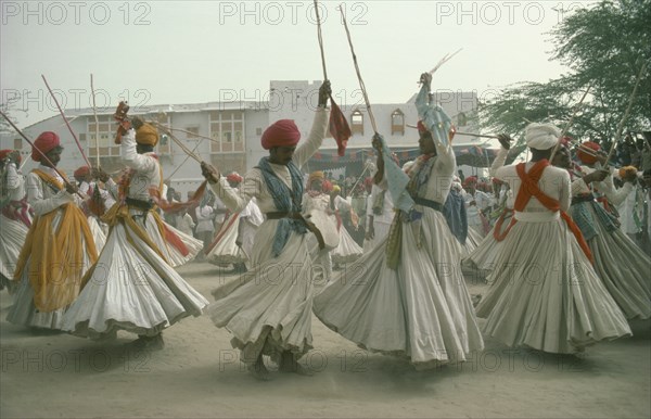 INDIA, Rajasthan, Jodhpur, Men dancing for the Maharaja of Jodhpur wearing traditional white robes and red turbans.
