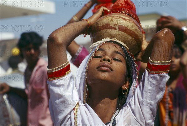 INDIA, Rajasthan, Udaipur, Young girl in trance carrying Holy Ganges water during memorial service.