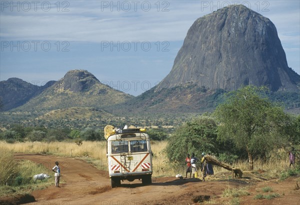 UGANDA, Karamoja, Minibus travelling along dirt road with people at the side