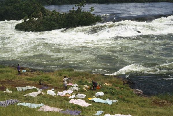 UGANDA, Bujagali Falls, View over the river and source of the Nile with people drying cloths on the bank in the foreground