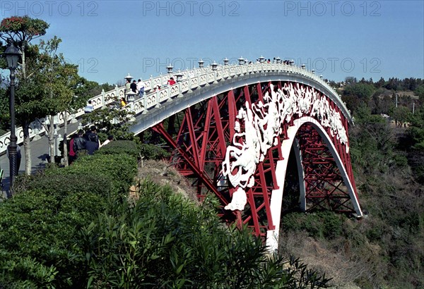 SOUTH KOREA, Cheju do Island, Peace Bridge. View along the red iron footbridge decorated with white carved figures