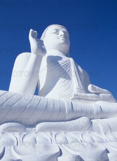 SRI LANKA, Mihintale, Angled view of large white seated Buddha seen from below looking up.